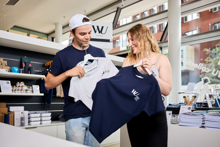 A man and a woman compare T-shirts in the WU Shop.